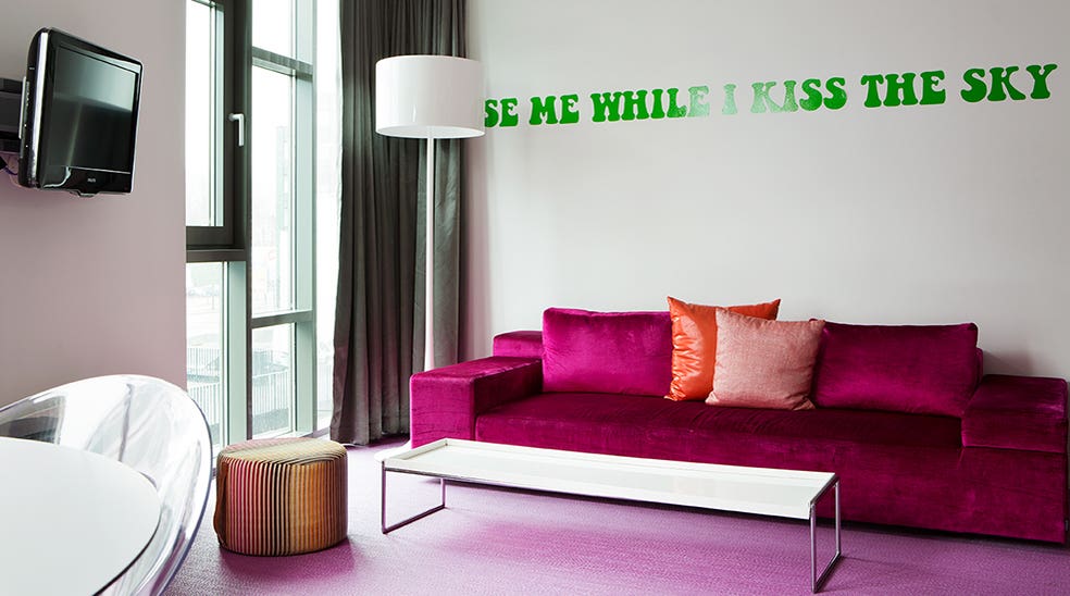 Suite Flowerpower rosa sofa og grønn tekst på veggen ved Comfort Hotel Union Brygge Drammen