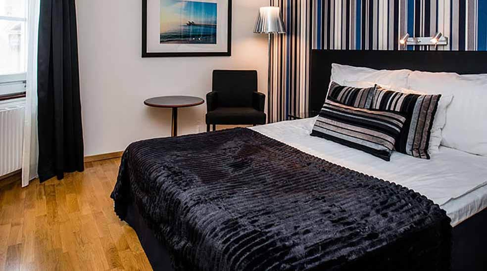Standard dobbeltrom med dobbeltseng, bord og lenestol samt stripete tapet på Quality Hotel Statt i Hudiksvall